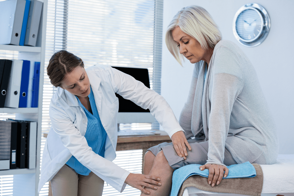 Dokter memeriksa pasien dengan arthrosis sendi lutut